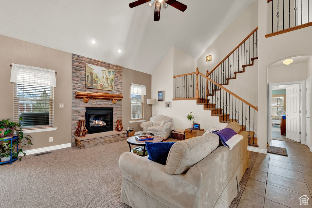 Carpeted living room featuring high vaulted ceiling, ceiling fan, and a fireplace