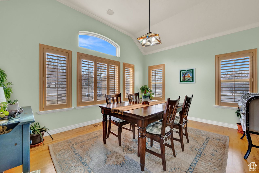 Dining space with vaulted ceiling, a healthy amount of sunlight, ornamental molding, and light hardwood / wood-style floors