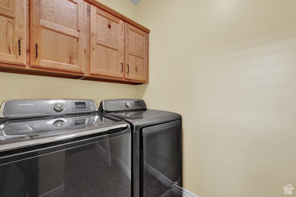 Clothes washing area with cabinets and washer and clothes dryer