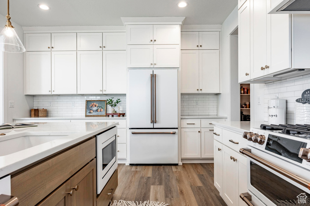 Kitchen with built in appliances, decorative light fixtures, and white cabinets