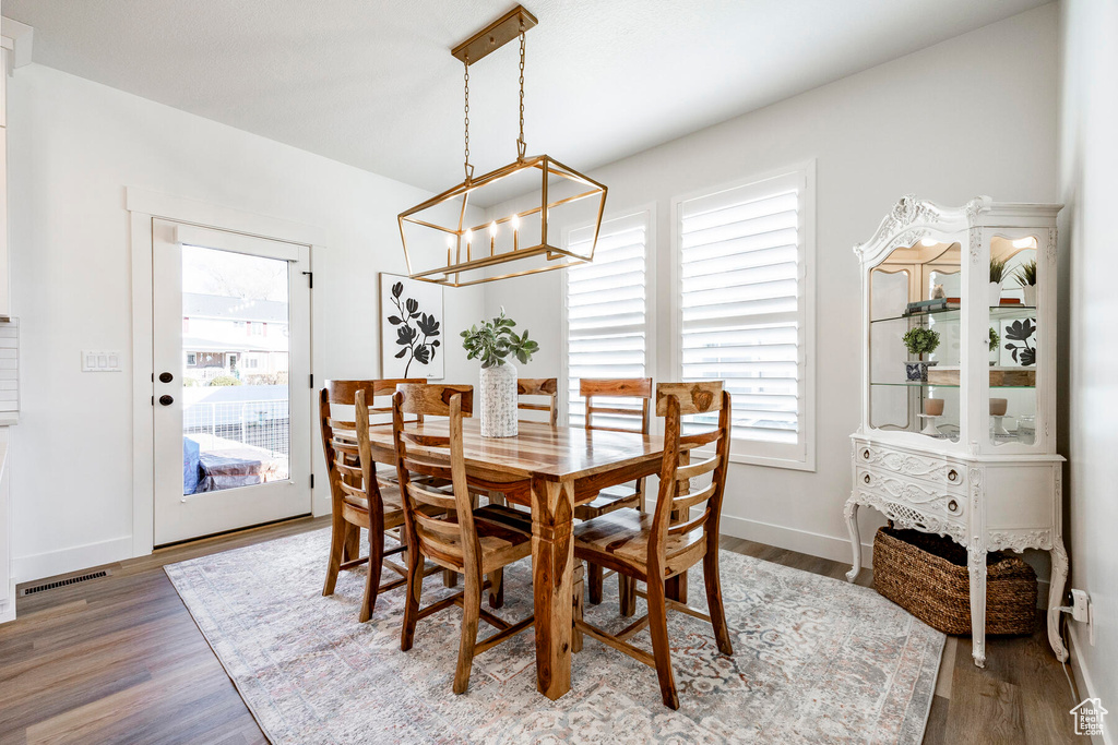 Dining space featuring a healthy amount of sunlight, light hardwood / wood-style floors, and a notable chandelier