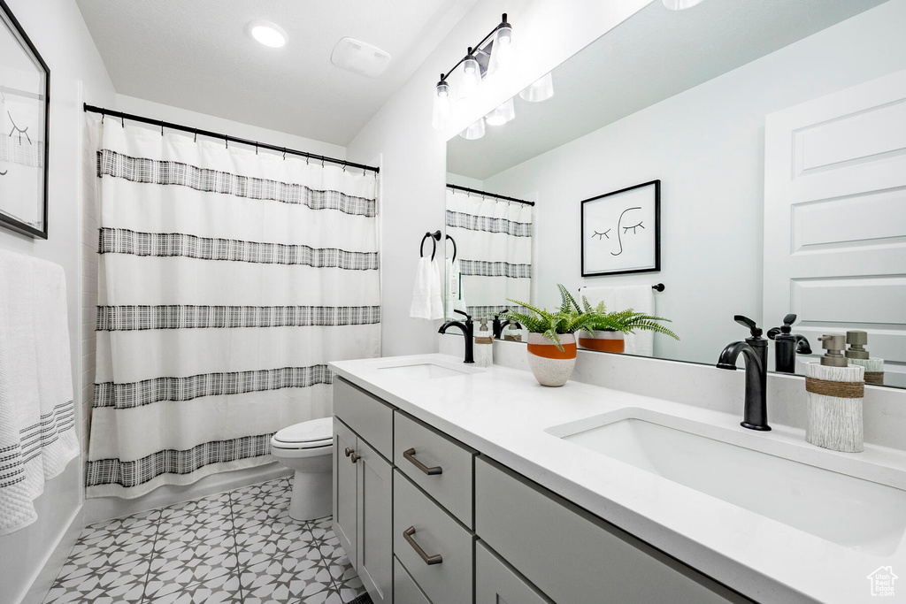 Bathroom featuring dual sinks, toilet, tile flooring, and large vanity