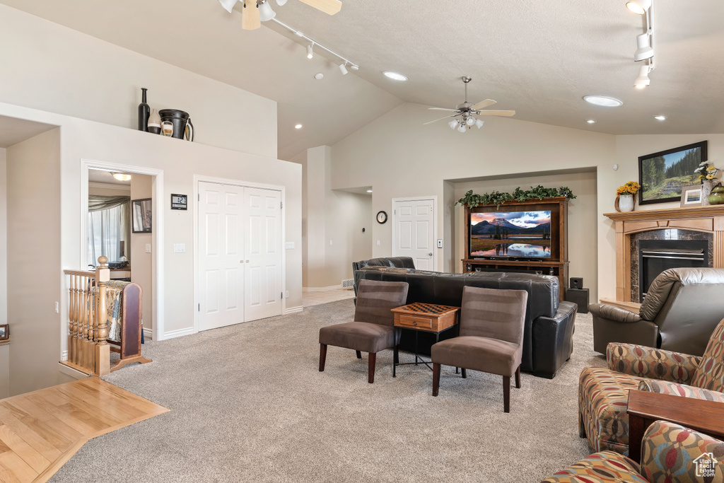 Living room featuring high vaulted ceiling, light colored carpet, rail lighting, and ceiling fan