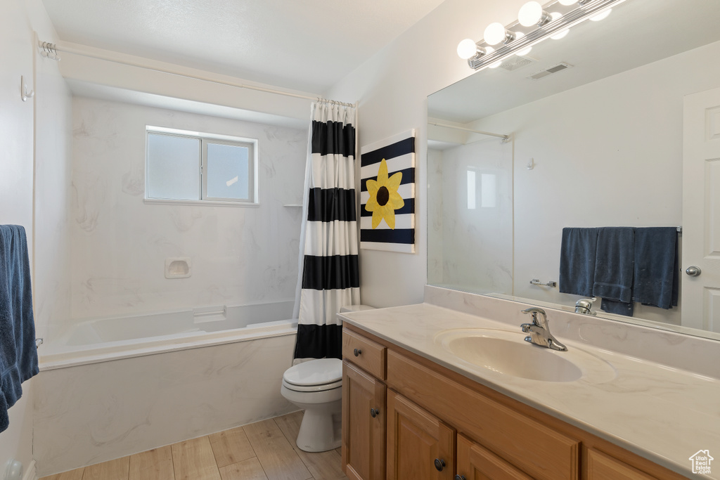Full bathroom featuring wood-type flooring, shower / bath combo, toilet, and vanity