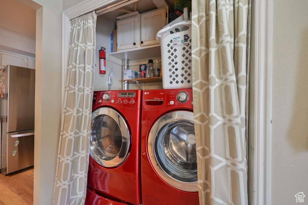 Laundry room with independent washer and dryer, cabinets, and light hardwood / wood-style floors