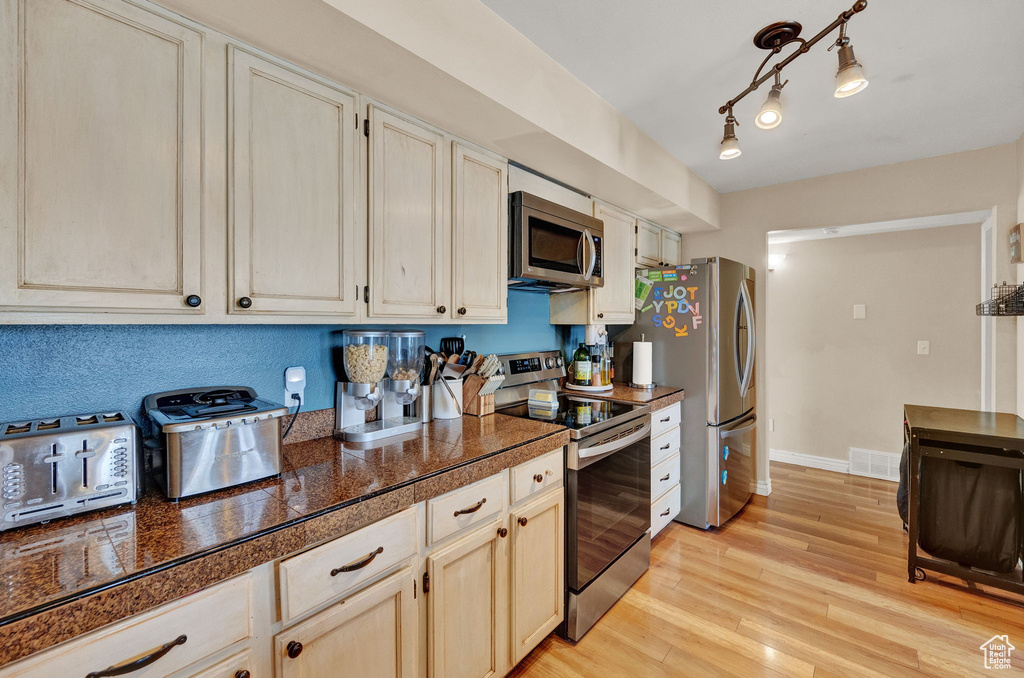 Kitchen featuring stainless steel appliances, rail lighting, and light hardwood / wood-style floors