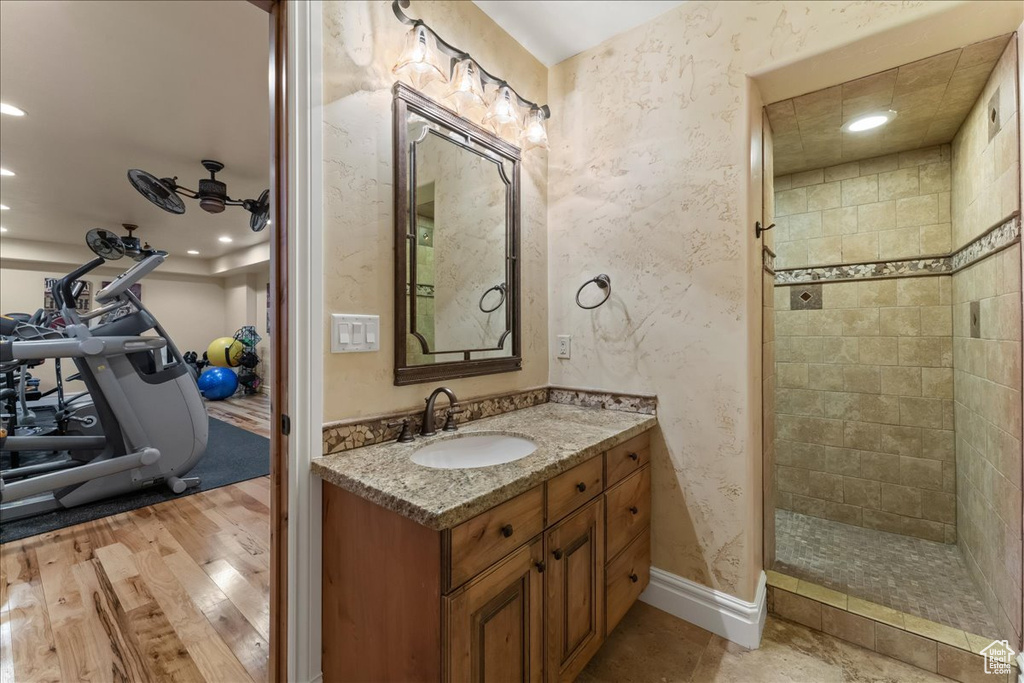 Bathroom featuring hardwood / wood-style flooring, vanity, and tiled shower