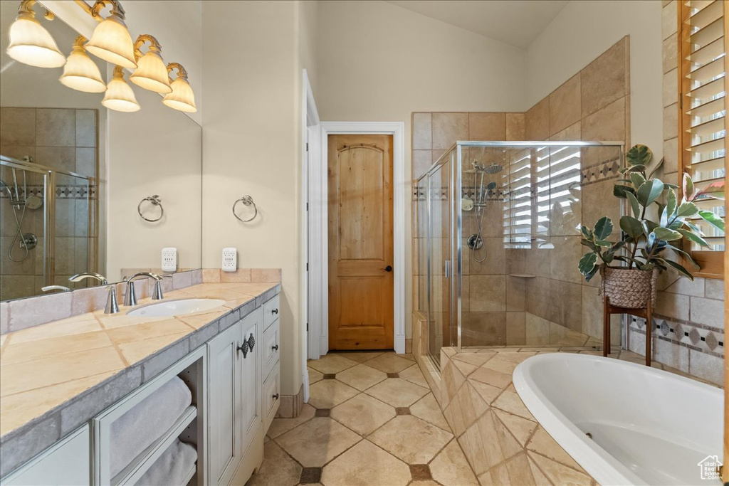 Bathroom featuring lofted ceiling, independent shower and bath, tile floors, and vanity