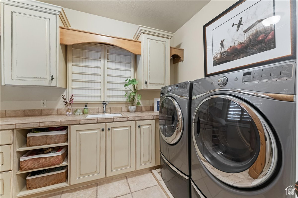 Laundry room with cabinets, light tile floors, sink, and independent washer and dryer