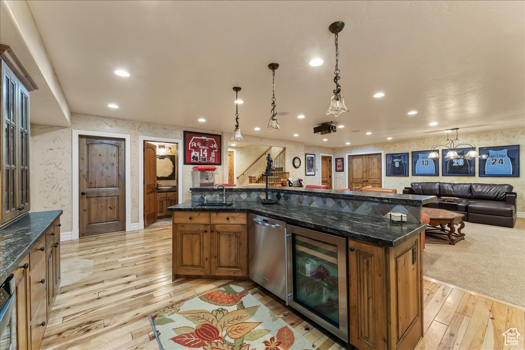 Kitchen featuring wine cooler, a center island with sink, dishwasher, and light hardwood / wood-style floors