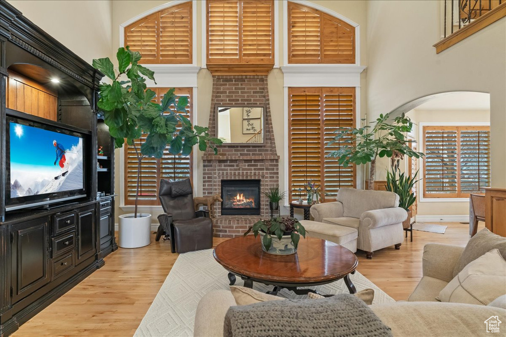 Living room featuring a fireplace, a high ceiling, and light hardwood / wood-style flooring