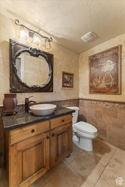 Bathroom featuring vanity, toilet, tile walls, and tile floors