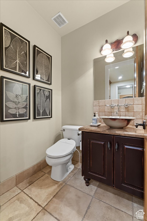 Bathroom with tile flooring, oversized vanity, tasteful backsplash, and toilet