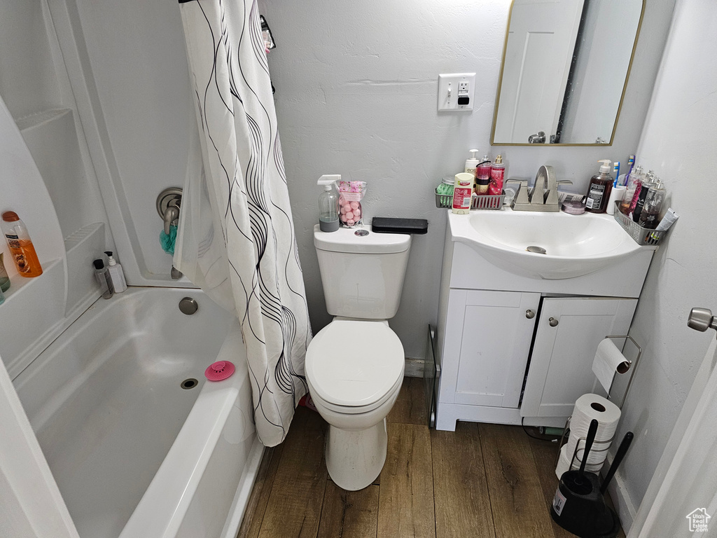 Full bathroom featuring vanity, toilet, hardwood / wood-style flooring, and shower / bathtub combination with curtain