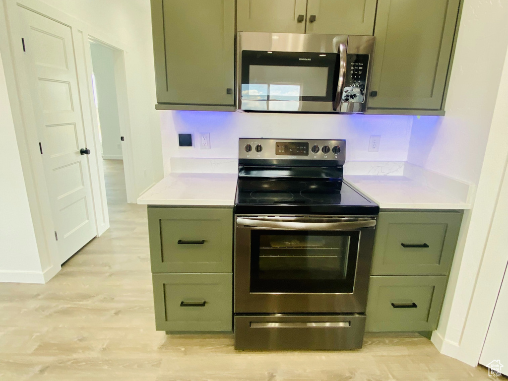 Kitchen featuring appliances with stainless steel finishes, light hardwood / wood-style floors, and green cabinets