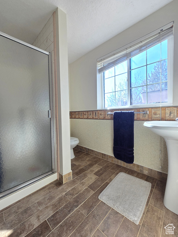 Bathroom with a textured ceiling, toilet, and walk in shower
