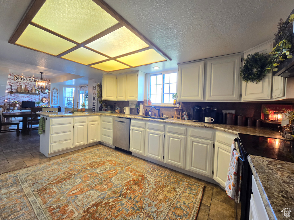 Kitchen featuring light tile flooring, a chandelier, dishwasher, sink, and range