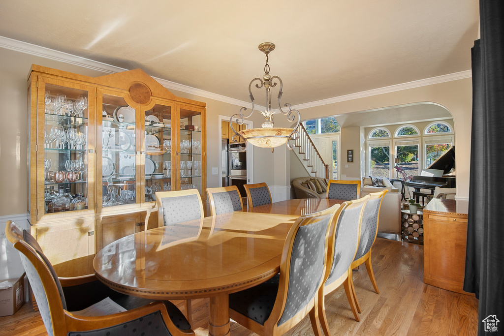 Dining area with light hardwood / wood-style flooring and crown molding