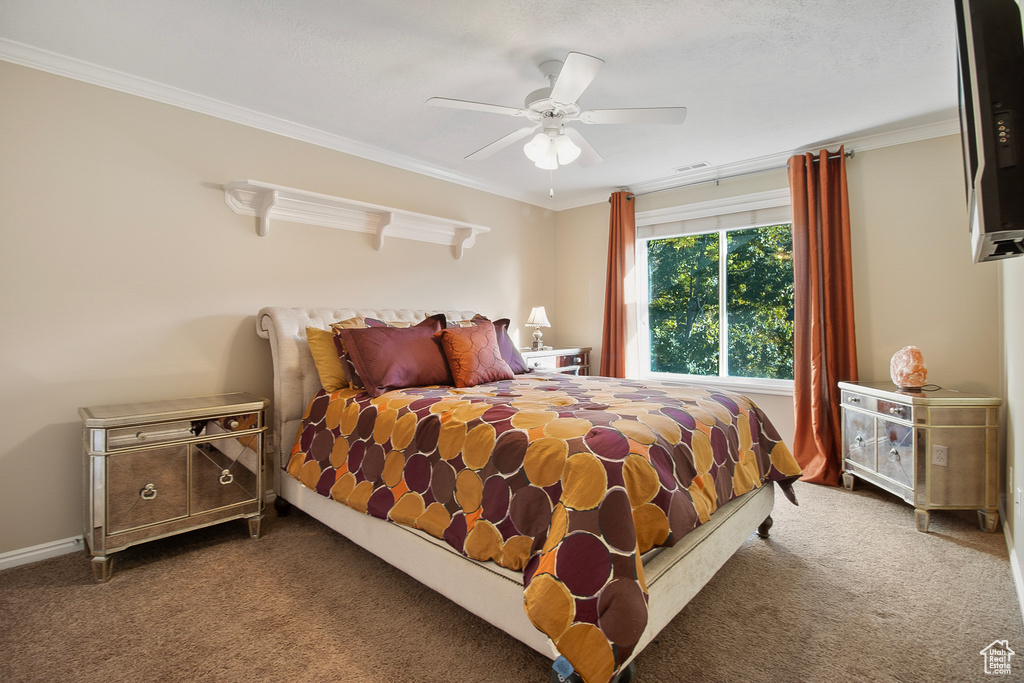 Bedroom featuring dark colored carpet, crown molding, and ceiling fan