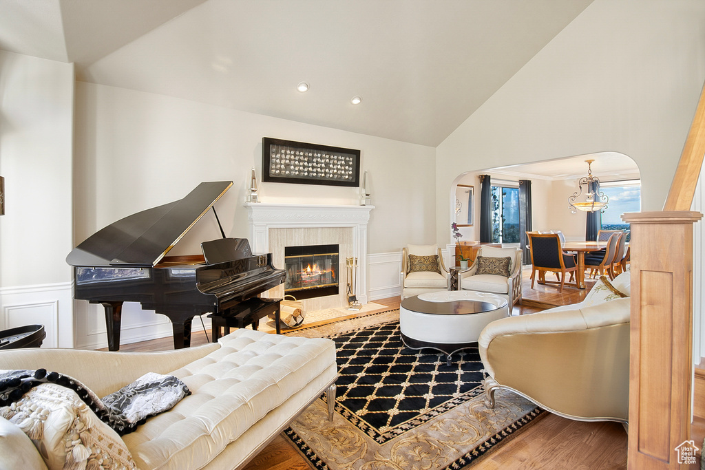 Living room featuring high vaulted ceiling, a notable chandelier, a fireplace, and hardwood / wood-style floors