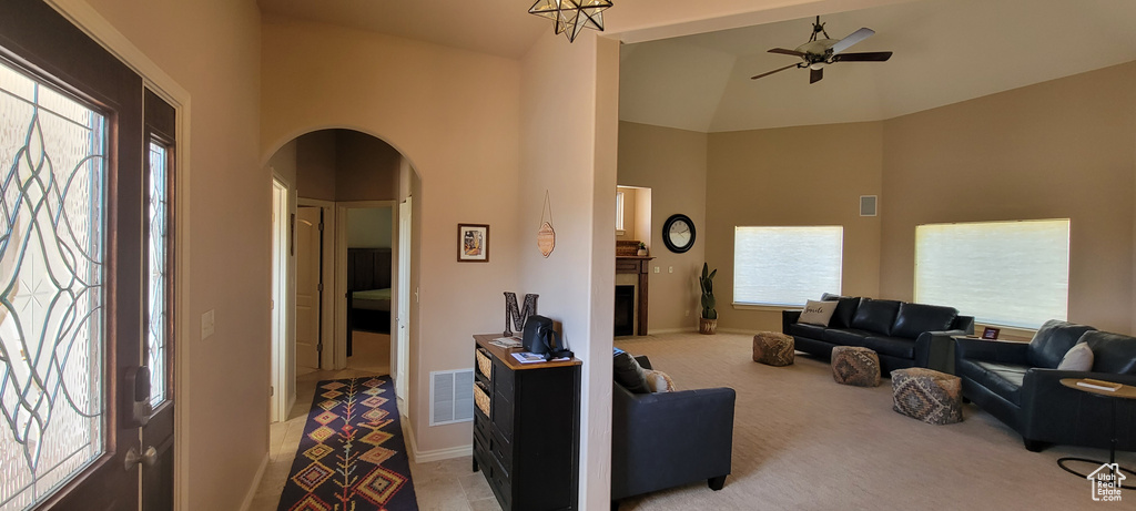 Carpeted living room with high vaulted ceiling and ceiling fan