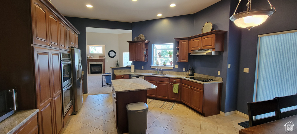 Kitchen featuring appliances with stainless steel finishes, light tile flooring, sink, pendant lighting, and a center island