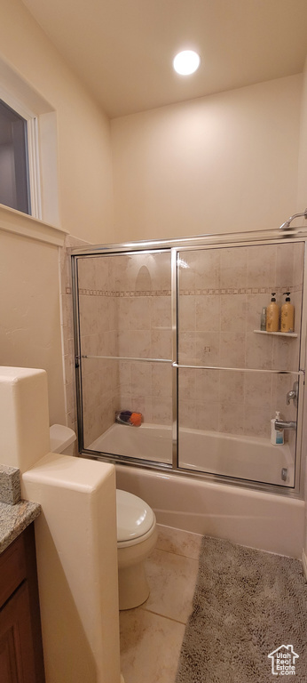 Full bathroom with vanity, toilet, shower / bath combination with glass door, and tile floors