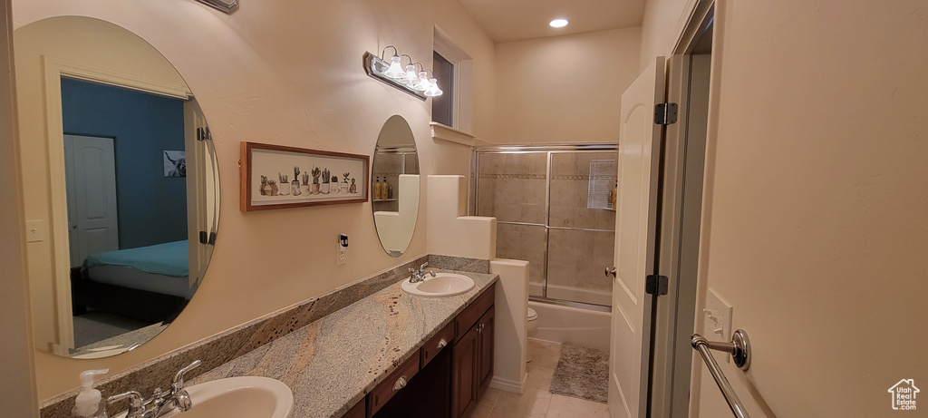 Full bathroom with toilet, tile floors, enclosed tub / shower combo, and dual vanity