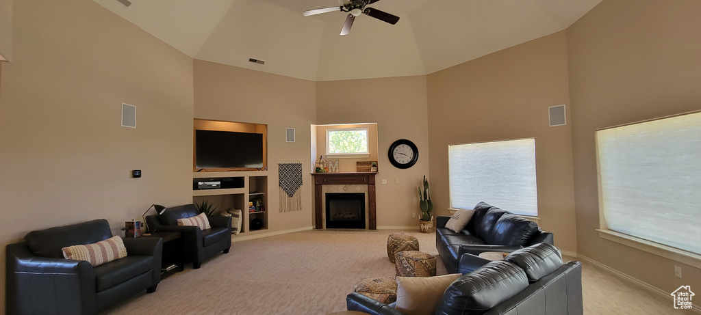 Living room with built in shelves, high vaulted ceiling, light colored carpet, and ceiling fan