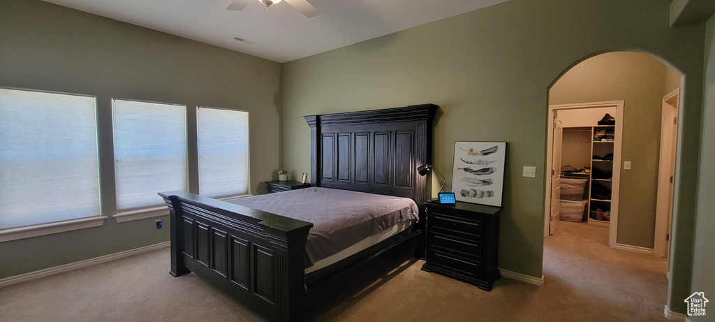 Carpeted bedroom with a walk in closet, a closet, and ceiling fan