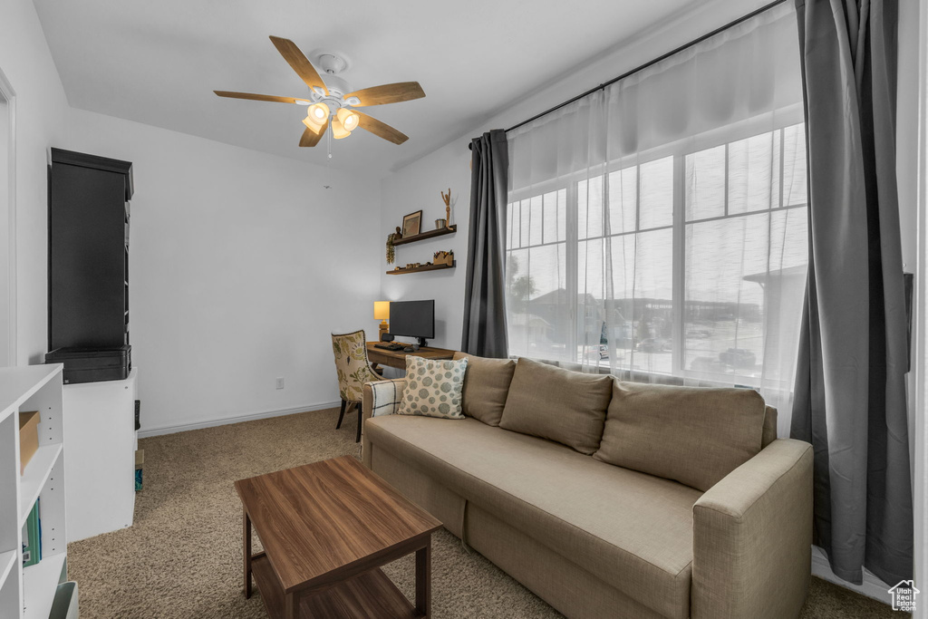 Carpeted living room featuring ceiling fan and a healthy amount of sunlight