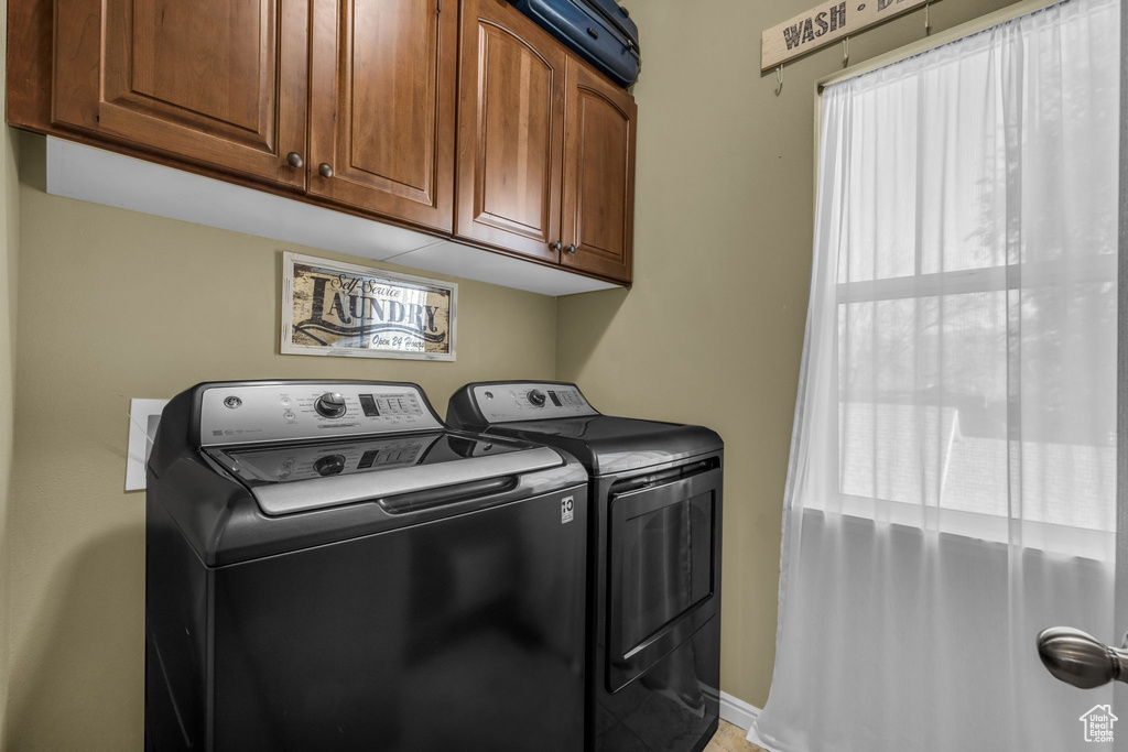 Washroom featuring cabinets and washer and clothes dryer