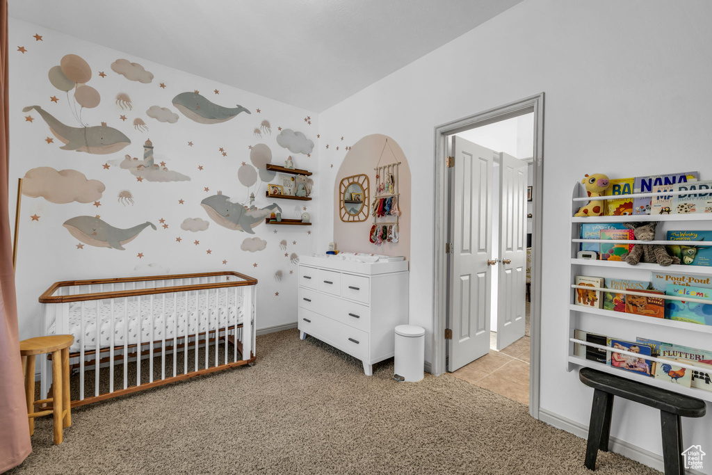 Bedroom featuring light colored carpet and a crib