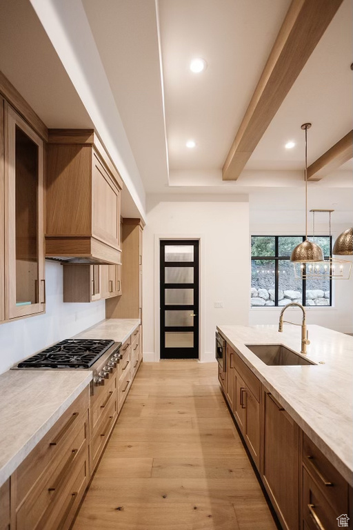 Kitchen featuring sink, premium range hood, decorative light fixtures, beam ceiling, and light hardwood / wood-style flooring