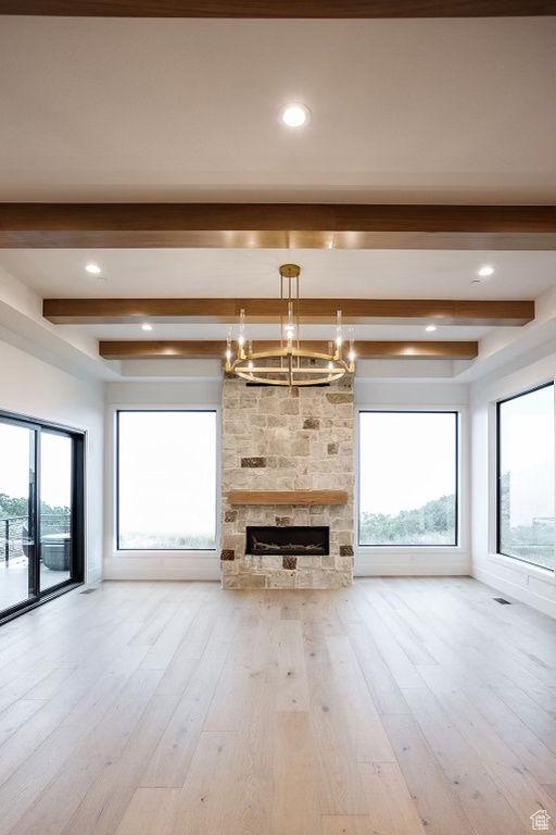 Unfurnished living room featuring a notable chandelier, light hardwood / wood-style flooring, and beam ceiling
