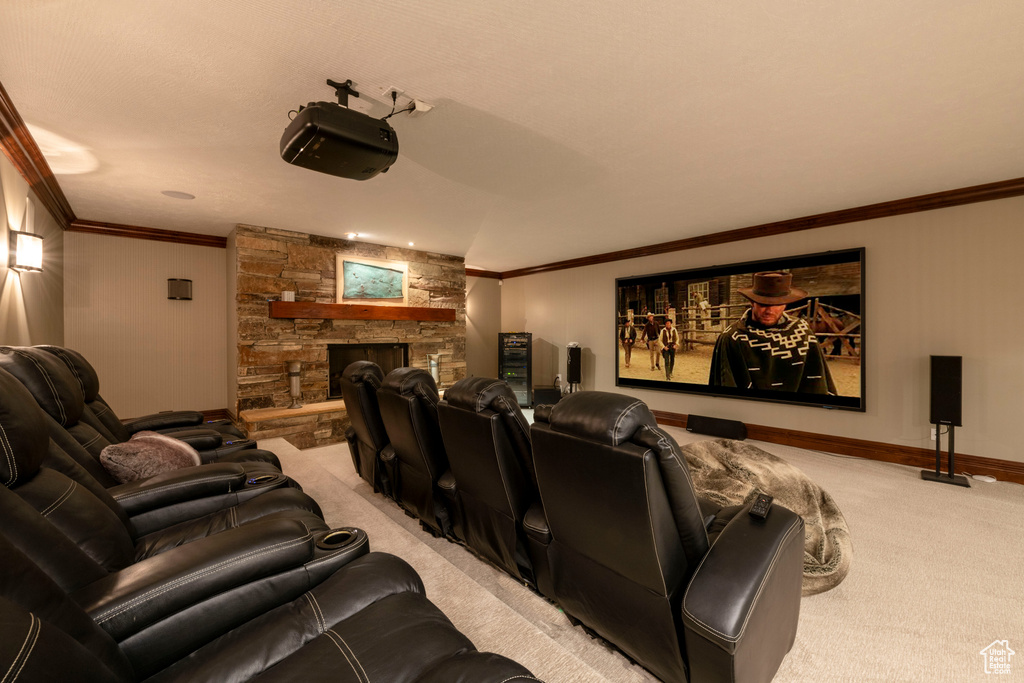 Cinema room with a stone fireplace, crown molding, and light carpet