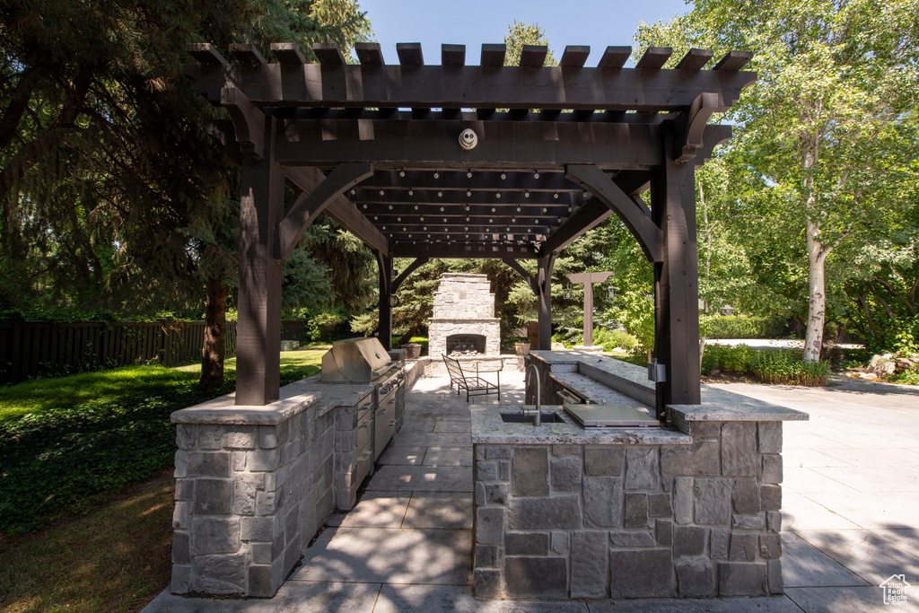 View of patio / terrace featuring an outdoor stone fireplace, area for grilling, and a pergola