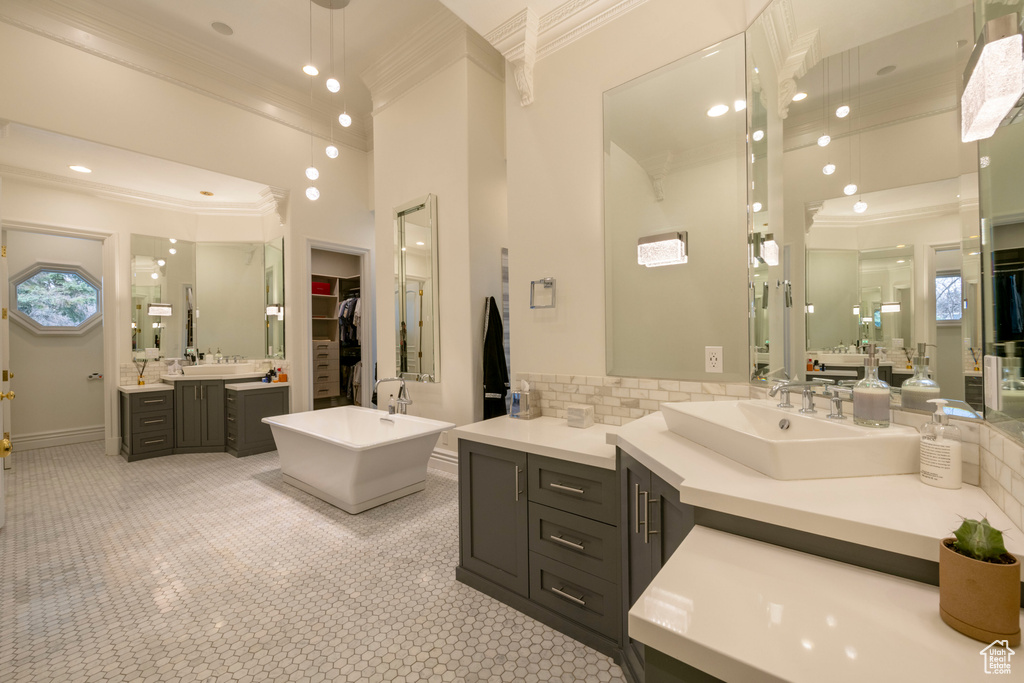 Bathroom featuring double sink, vanity with extensive cabinet space, tile floors, and crown molding
