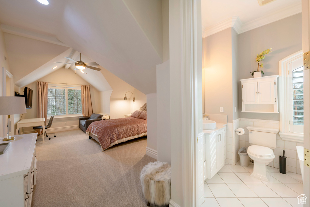 Bedroom featuring ensuite bathroom, light tile flooring, ceiling fan, tile walls, and ornamental molding