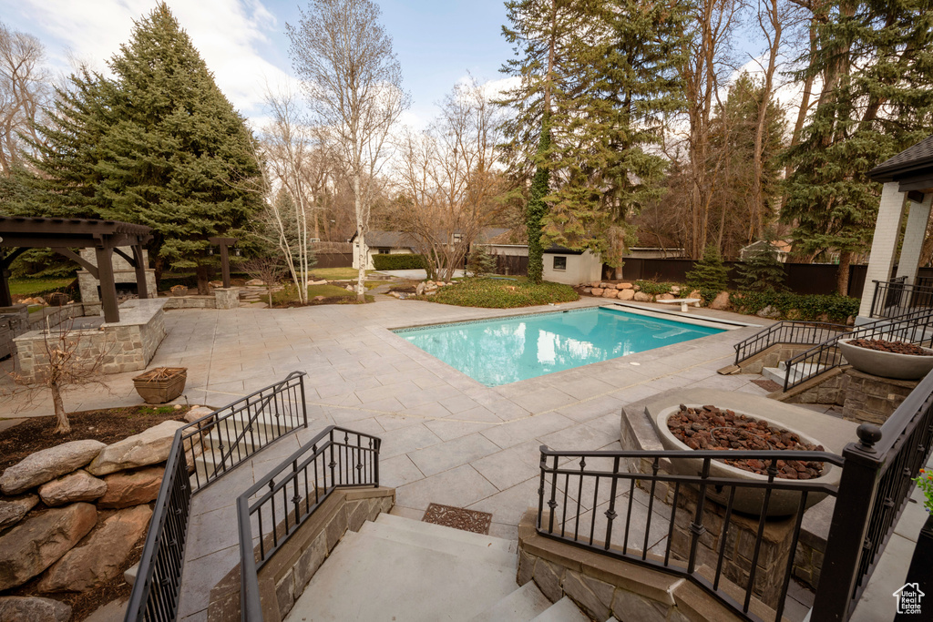 View of swimming pool with a patio area and a fire pit
