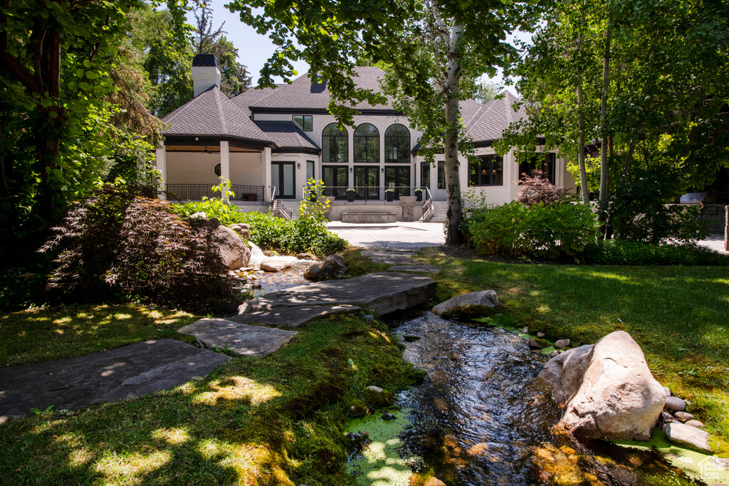 Back of property featuring a chimney, a lawn, and stucco siding