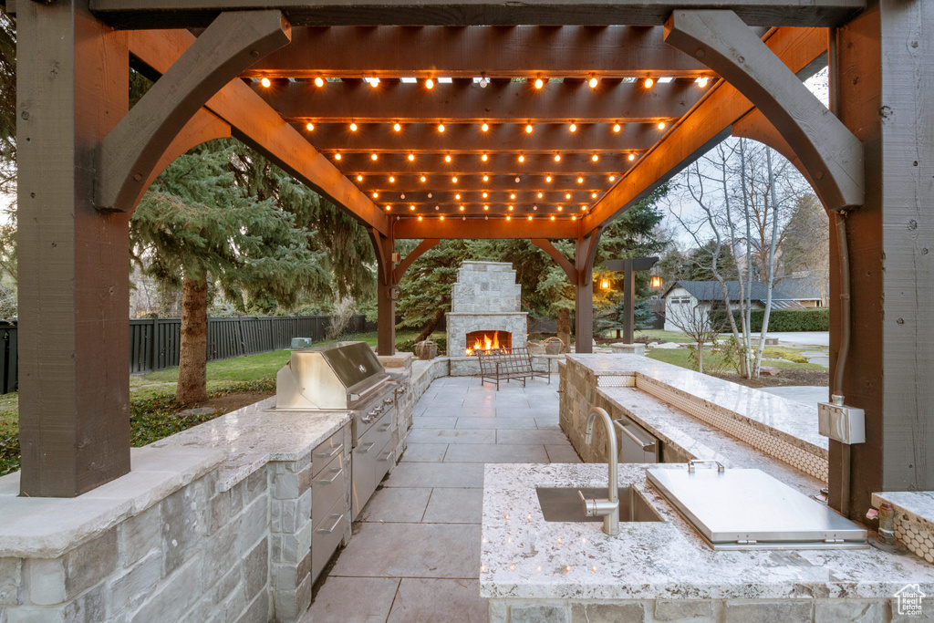 View of patio with a pergola, an outdoor stone fireplace, and exterior kitchen