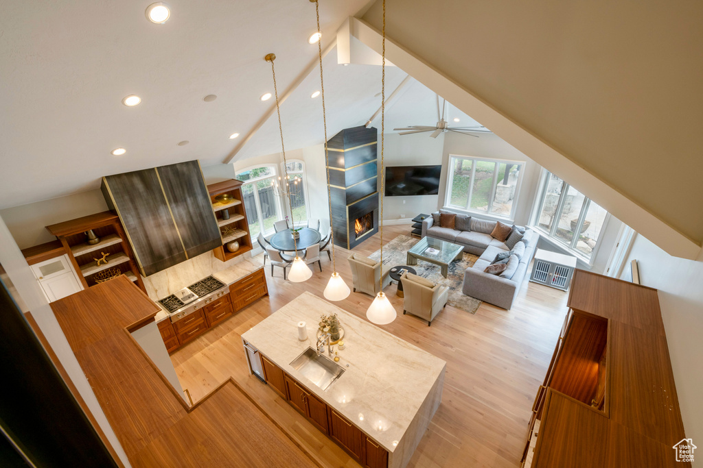 Living room featuring high vaulted ceiling, ceiling fan, and light hardwood / wood-style floors