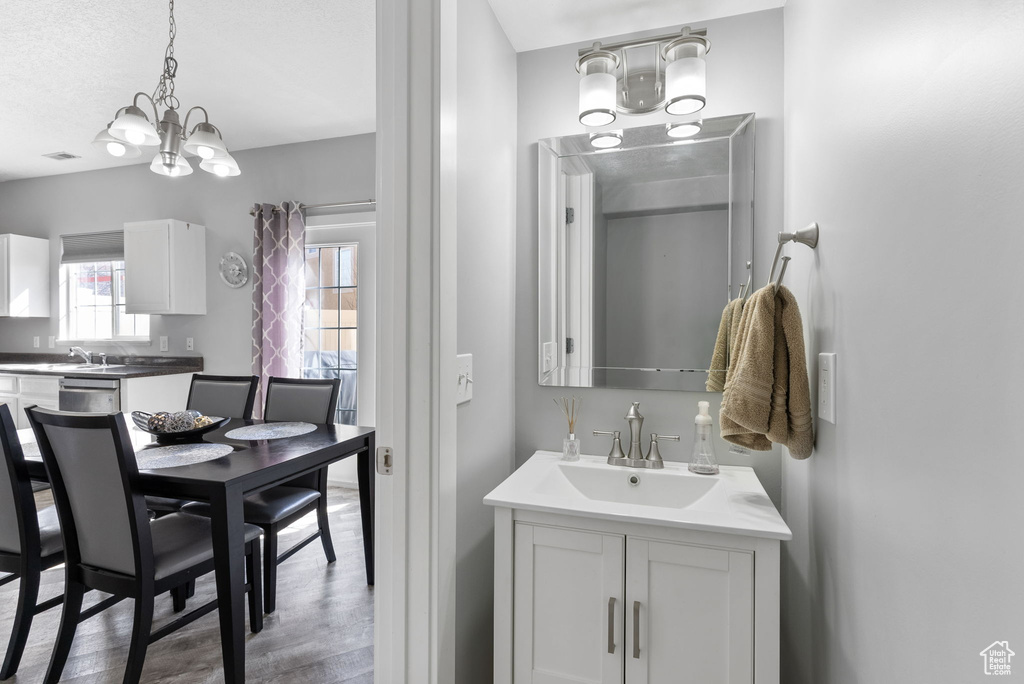 Bathroom featuring a notable chandelier, large vanity, and wood-type flooring