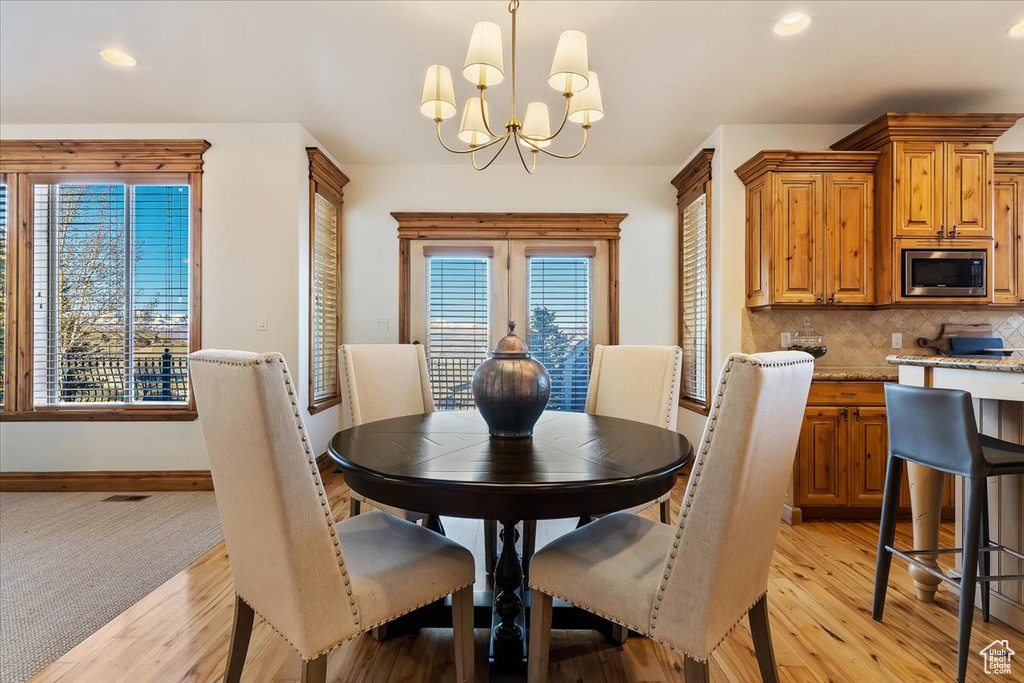 Dining room featuring an inviting chandelier, plenty of natural light, and light hardwood / wood-style floors