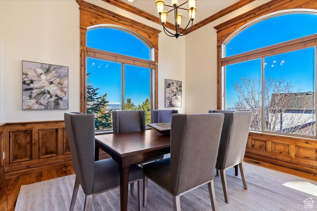Dining space with a wealth of natural light, a chandelier, crown molding, and light hardwood / wood-style flooring
