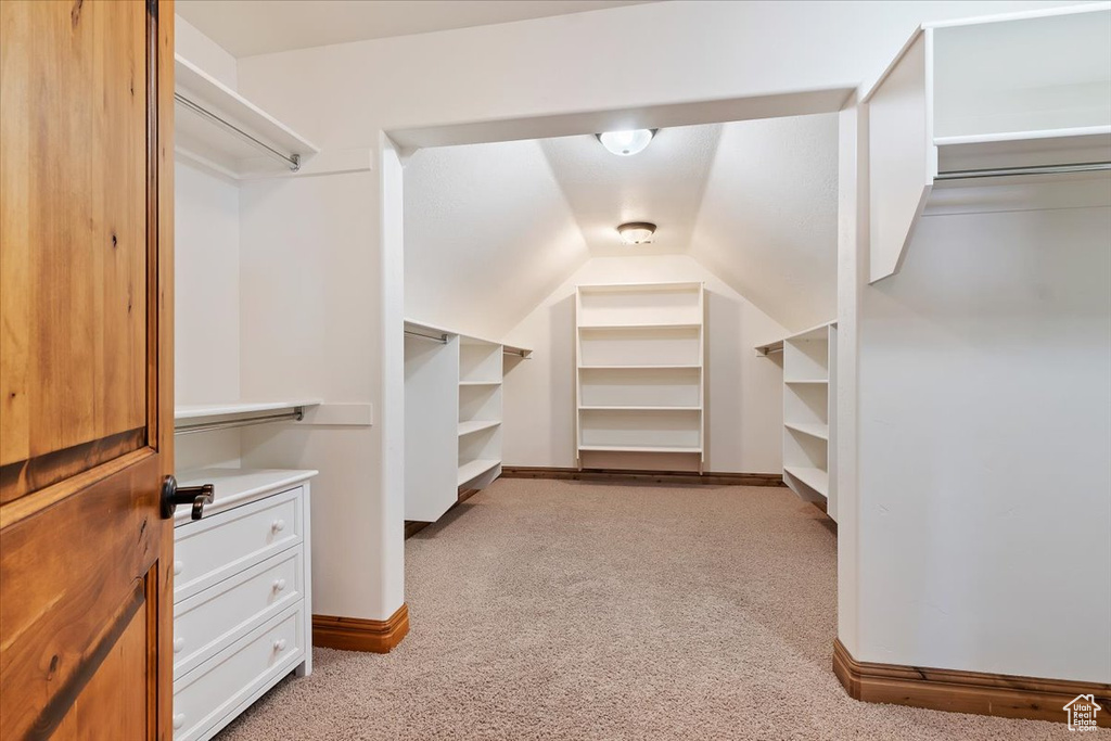 Spacious closet featuring light carpet and vaulted ceiling