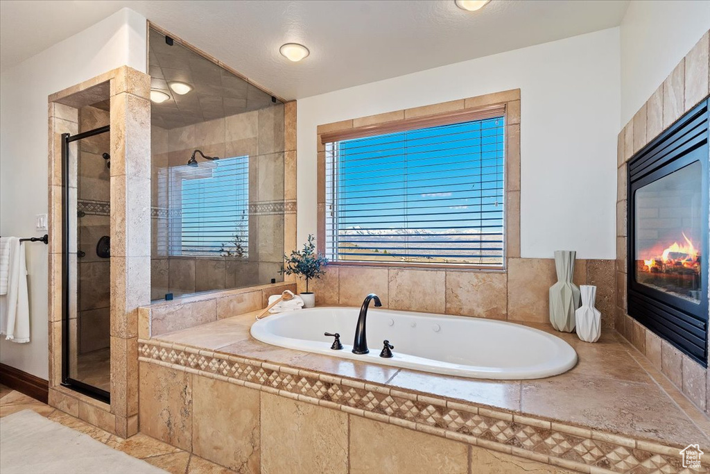 Bathroom with tile flooring, a tile fireplace, and separate shower and tub