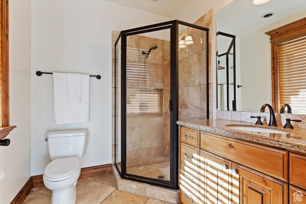 Bathroom featuring a shower with shower door, tile floors, large vanity, and toilet