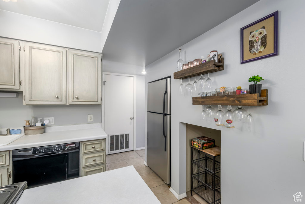 Kitchen with black dishwasher, stainless steel fridge, and light tile floors